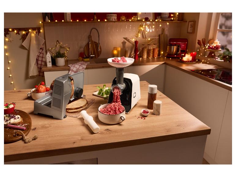 Vleesmolen en broodsnijder op een kerstversierd aanrecht.