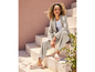 Een vrouw draagt een beige broekpak en beige sandalen.