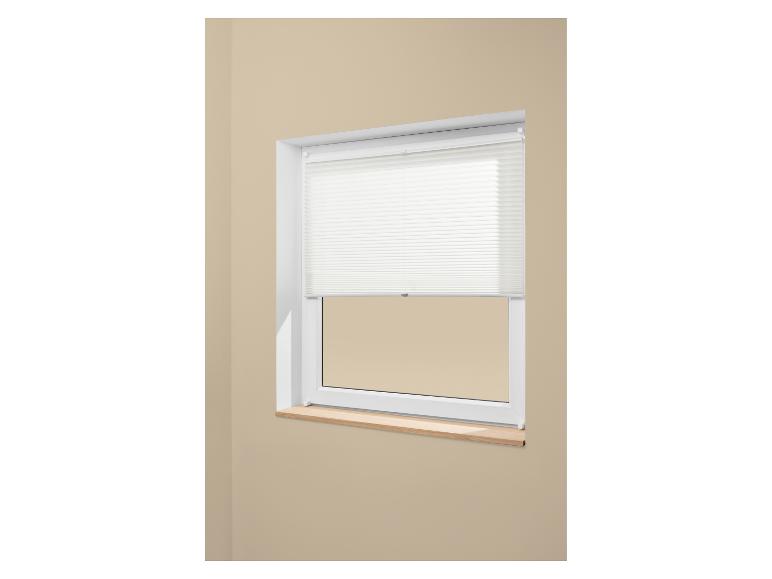 Fenêtre avec store plissé blanc et rebord de fenêtre en bois clair sur un mur beige.
