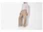 Vrouw draagt een witte top met lange mouwen en een beige wijde broek met zijstrepen