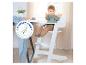 Baby in witte kinderstoel aan tafel, met EN 14988:2017+A1:2020 markering.