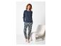 Vrouw in blauwe pyjama met patroon en shirt met lange mouwen, naast een witte stoel.