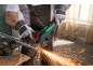 Arbeider snijdt een metalen buis in een bankschroef met een haakse slijper.
