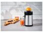 Presse-agrumes en acier inoxydable avec un pamplemousse et un verre de jus frais sur un comptoir de cuisine.