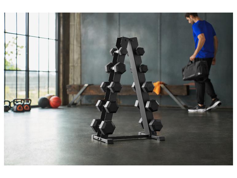 Een man loopt in een sportschool met een halterrek en apparatuur.