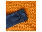Mouw van een blauwe wollen trui op een oranje wafelpatroon deken.