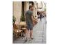 Man in groen T-shirt met palmboomprint en grijze korte broek loopt over een straat.