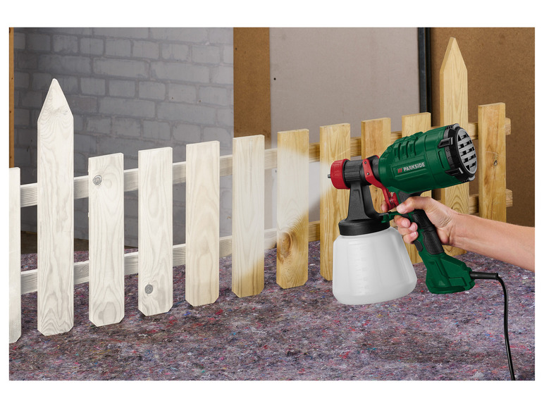 Une pistole à peinture Parkside est utilisée pour peindre une clôture en bois.