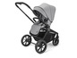 Een grijze kinderwagen met zwarte wielen en een leren handvat.