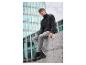 Un homme porte un pull noir et un pantalon gris avec des bottes Timberland noires.