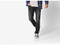 Man draagt een blauw geruit overhemd, licht T-shirt, donkere jeans en sneakers.