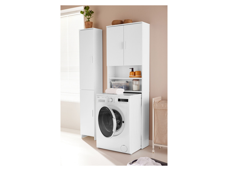 Een witte wasmachine met een wit kastje erboven.