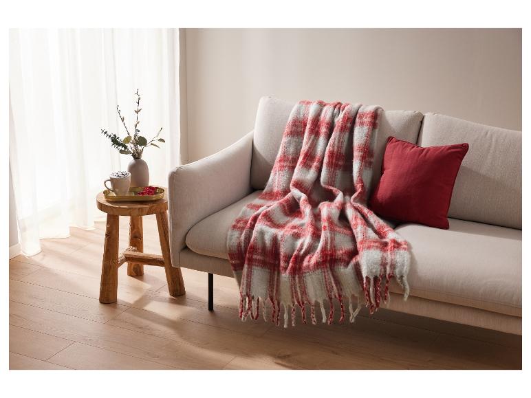 Un canapé avec une couverture à carreaux rouge et blanc et un coussin.