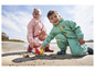 Deux enfants jouent sur la plage avec des vêtements imperméables et des pelles.