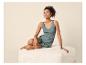 Femme en pyjama débardeur vert et short imprimé, assise sur un pouf.