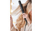 Een vrouw gebruikt een zwarte Remington haarstyler om haar haar te stylen.