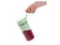 Main tenant un mixeur portable Silvercrest vert menthe avec un smoothie rouge.
