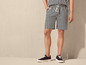 Man draagt gestreepte korte broek en zwarte sneakers.