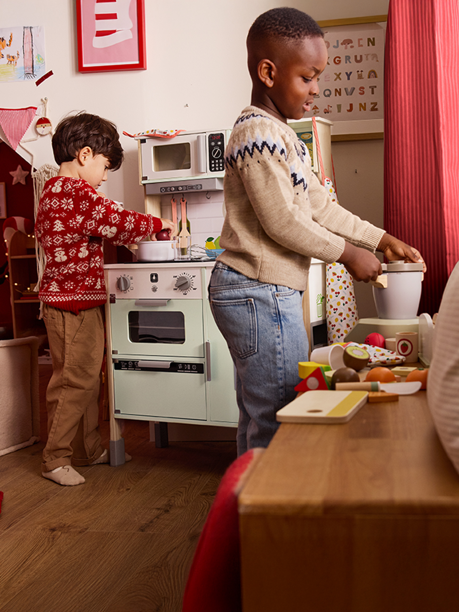 Twee kinderen spelen met een speelkeuken en speelgoedeten in een feestelijk ingerichte kamer.