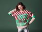 Une femme porte un pull de Noël avec 'Santa' et un pantalon argenté.