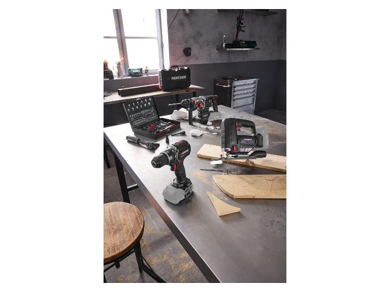 Perceuse sans fil, scie sauteuse et perforateur sur un établi dans un atelier.