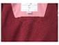 Close-up van een rood fleece kledingstuk met roze binnenvoering en een 'Buiten bereik van vuur houden'-label.