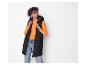 Vrouw in zwart gewatteerd vest, oranje shirt en jeans.
