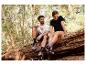 Homme et femme en t-shirts et baskets de sport assis sur une bûche dans la forêt.
