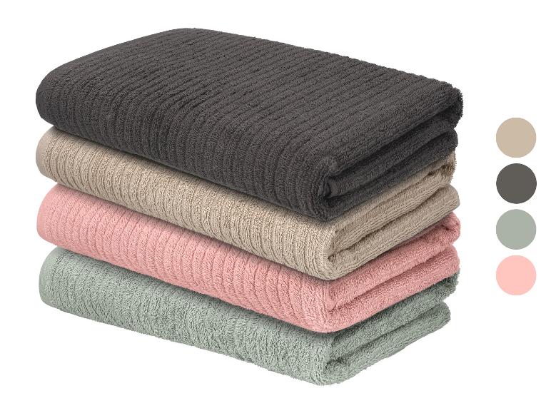 Een stapel van vier gevouwen geribbelde handdoeken in donkergrijs, beige, roze en lichtgroen.
