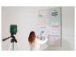 Femme utilisant un niveau laser pour aligner quatre tableaux sur un mur.