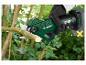 Een gehandschoende hand snoeit een tak met een groene PARKSIDE X 20V TEAM accuschaar.