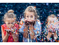 Drie meisjes blazen kleurrijke confetti, vrolijk plezier.