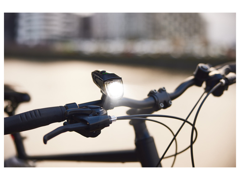 Een close-up van een fietsstuur met een koplamp en versnellingshendel.