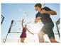 Deux joueurs de badminton, un homme et une femme, sur un court extérieur.