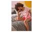 Une femme sur un lit, portant un pyjama rose pour femme Minnie Mouse.
