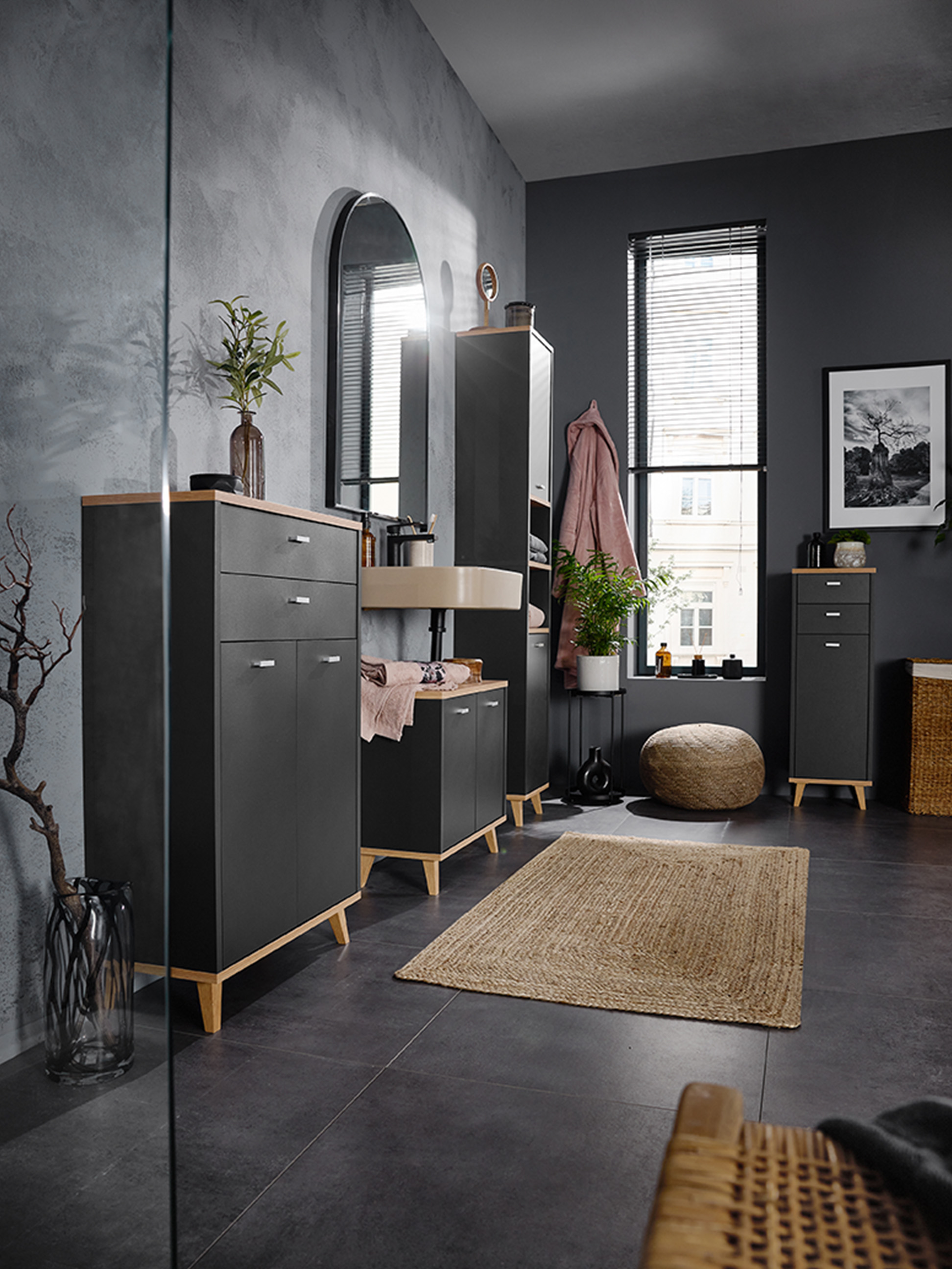 Badkamer met donkergrijze kasten, houten details en een wandgemonteerde wastafel.