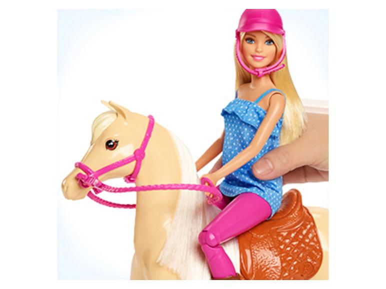 Barbiepop rijdend op een speelgoedpaard, vastgehouden door een menselijke hand.