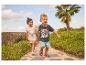 Deux enfants marchent sur un chemin, la fille porte un haut imprimé princesse, le garçon un t-shirt imprimé super-héros.