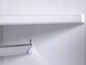 Een witte plank en een chromen handdoekhouder in een badkamer.