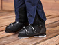 Zwarte ski-laarzen met blauwe ski-broek op een houten vloer.