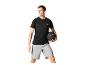 Man in zwart sportshirt en grijze korte broek met een zwarte trainingsbal.