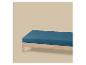 Een blauw matras op een houten frame tegen een beige achtergrond.