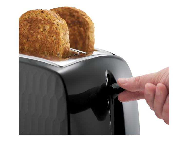 Doigt appuyant sur le levier d'un grille-pain noir avec deux tranches de pain grillé.
