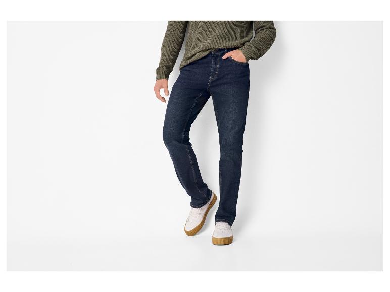 Homme portant un pull en maille vert foncé, un jean bleu foncé et des baskets blanches à semelles marron.