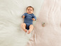 Un bébé souriant dans un body rayé sur une couverture