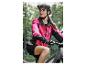 Vrouw in roze fietsjack en zwarte helm op een mountainbike.