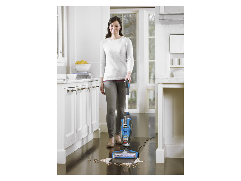 Een vrouw gebruikt een Bissell CrossWave-stofzuiger in een keuken.