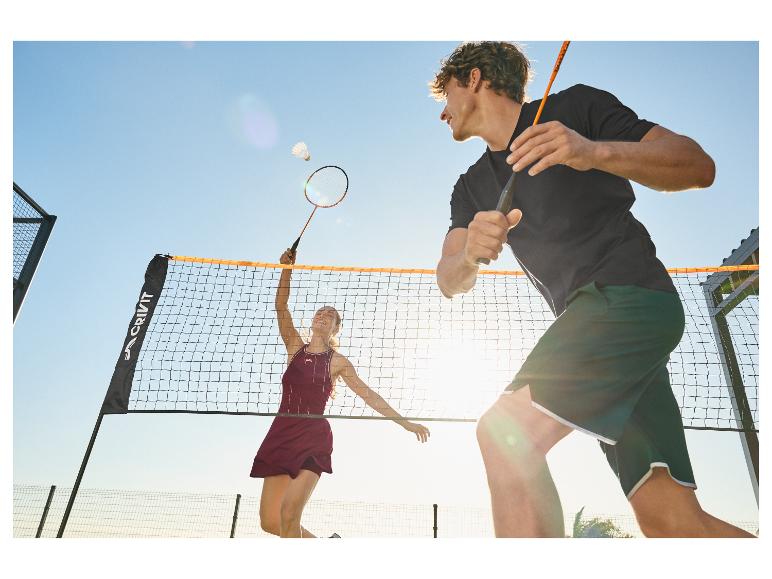 Deux joueurs de badminton, un homme et une femme, sur un court extérieur.