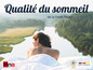 Femme dans un lit Hns avec vue sur une rivière et une forêt.