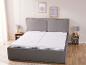 Een grijs bed met een matras en houten nachtkastjes